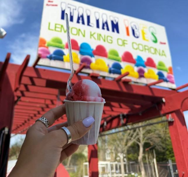 A rainbow Italian ice in front of the Italian ices sign