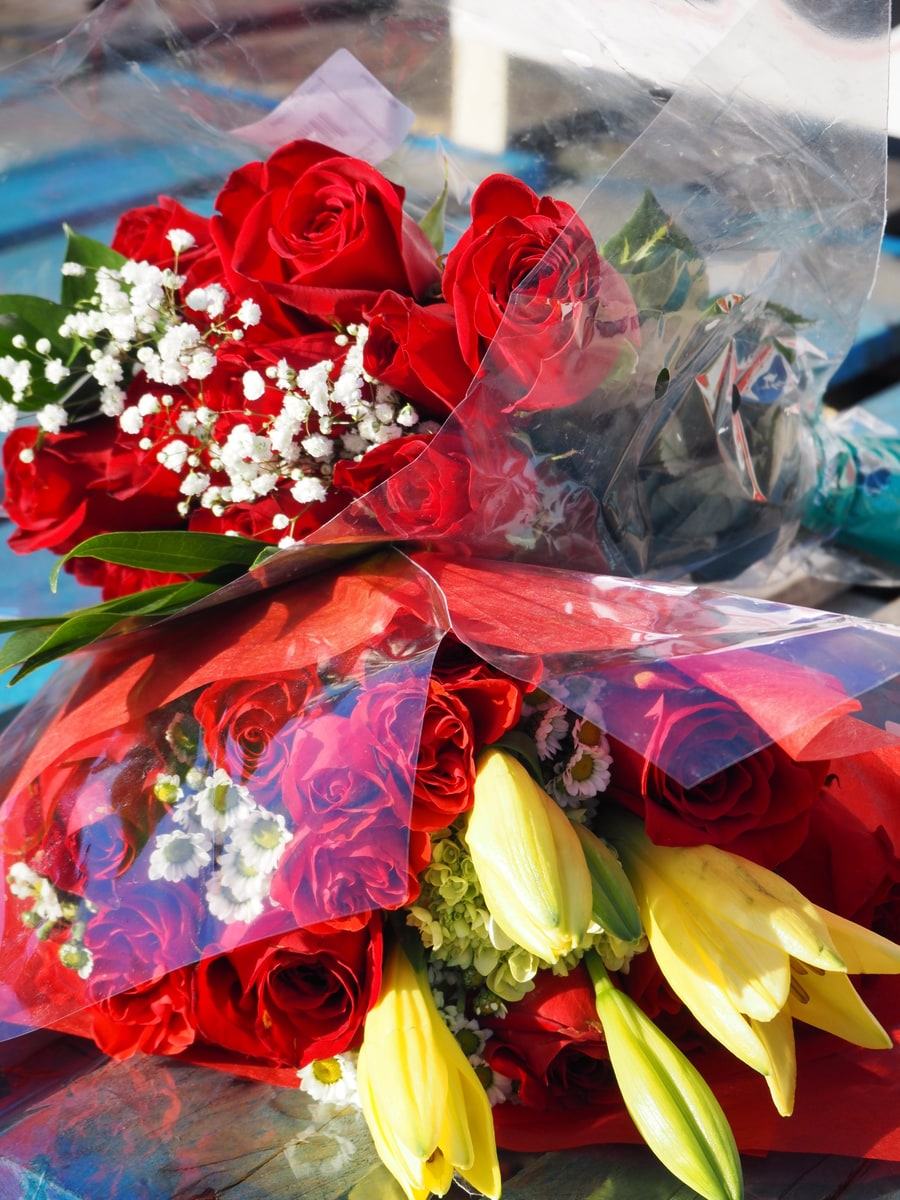 Bouquets of red roses, lilies and baby's breath wrapped and ready to go
