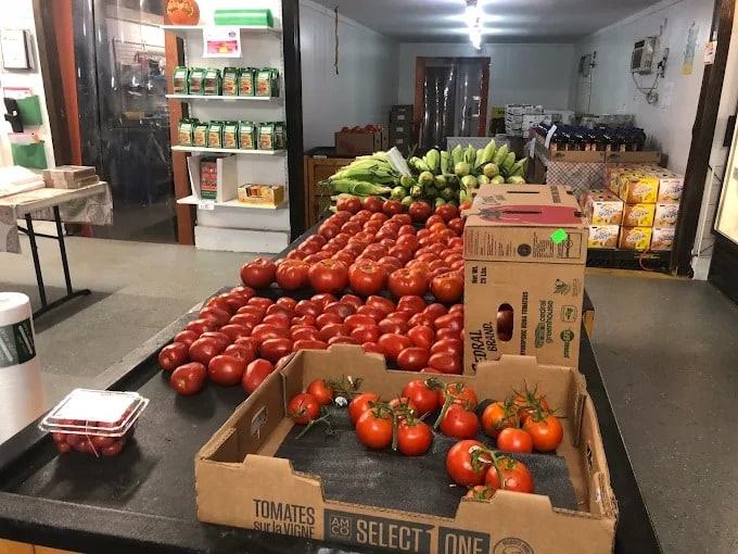 Fresh tomatoes and ears of corn on the counter inside the store