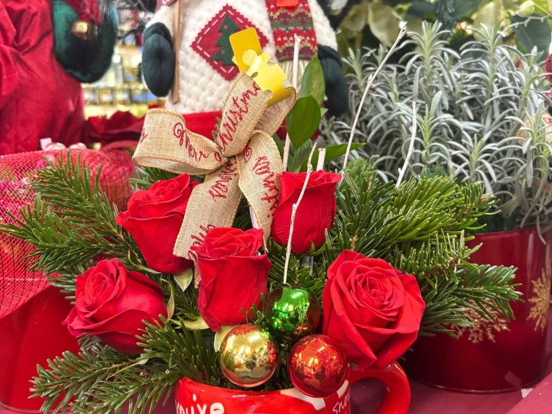 A holiday arrangement of red roses, pine and ornaments