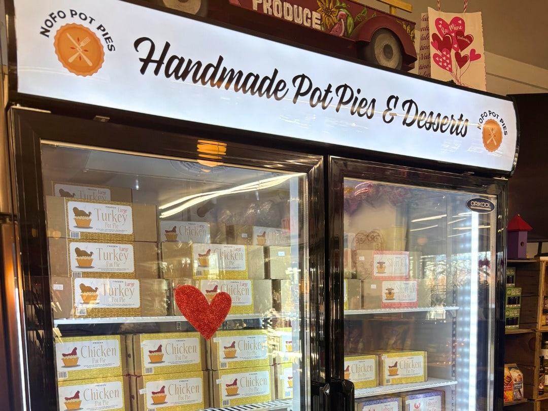 A freezer case under a Handmade Pot Pies and Desserts sign